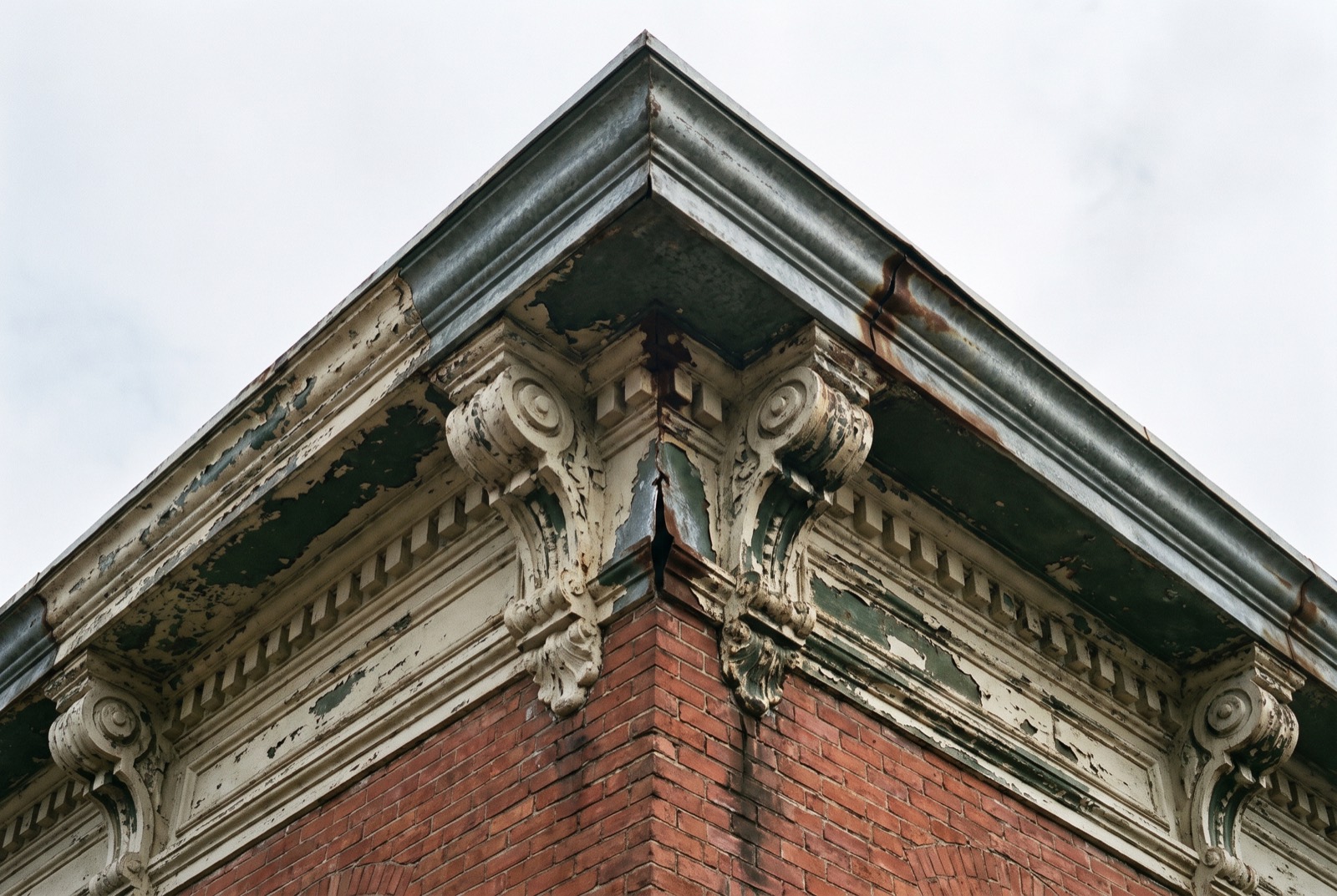 A weathered pressed-metal cornice with rust streaks and an open seam